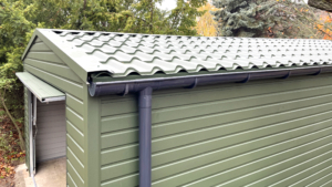 4x7m-es delux mobilgarázs nyeregtetővel, sötétzöld falakkal, 1db billenőkapuval, ajtóval, 2db ablakkal, szegélyekkel, ereszcsatornával, horganyzott vázszerkezettel, vízszintes lemezeléssel