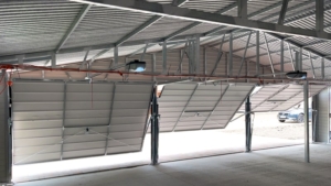 10,5x7m-es delux mobilgarázs nyeregtetővel, sötét diófa falakkal, 3db billenőkapukkal, ajtóval, 2db ablakkal, szegélyekkel, ereszcsatornával, horganyzott vázszerkezettel, vízszintes lemezeléssel