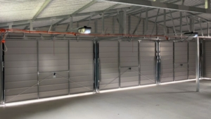 10,5x7m-es delux mobilgarázs nyeregtetővel, sötét diófa falakkal, 3db billenőkapukkal, ajtóval, 2db ablakkal, szegélyekkel, ereszcsatornával, horganyzott vázszerkezettel, vízszintes lemezeléssel