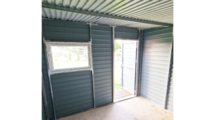 3x3m-es delux fém kerti tároló hátra lejtő tetővel, fahatású szürke színben, ajtóval, ablakkal, ereszcsatornával, szegélyekkel, horganyzott vázszerkezettel, vízszintes lemezborítással